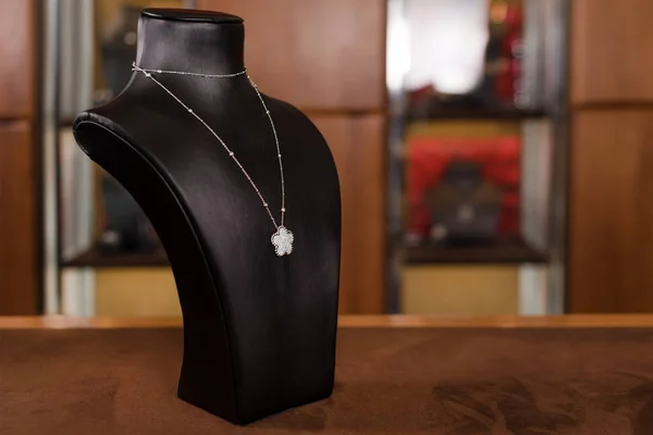 Fehér aranyból készült nyaklánc gyémántokkal a divatos ékszerbolt standján. Fekete állvány nyak luxus ékszerek, női tartozékok a bolt ablakában. — Stock Fotó