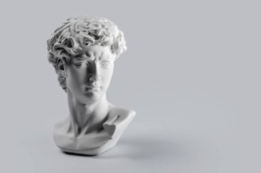 David 'in kafasının alçıtaşı heykeli. Michelangelo 'nun David heykeli alçıdan yapılmış gri arkaplan ve metin için telif alanı var. Antik Yunan heykeli, kahraman heykeli.