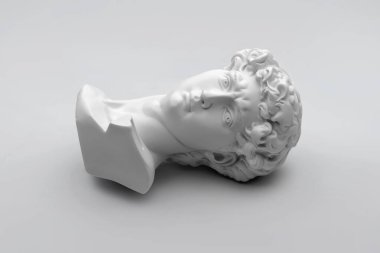 Alçı taşı büstü, David 'in kafasının heykeli. Michelangelo 'nun David heykeli gri arka planda alçıdan yapılmış. Antik Yunan heykeli, kahraman heykeli.