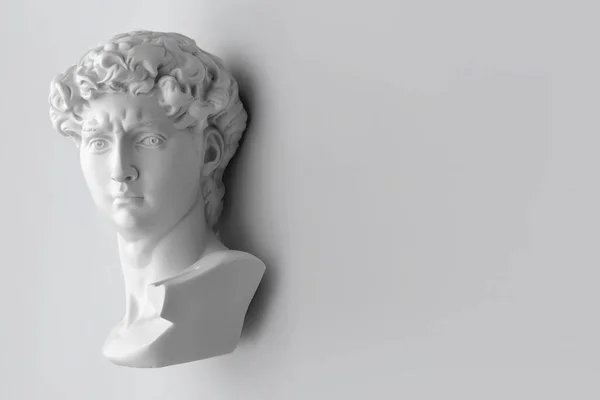 Gypsum statue of David\'s head. Michelangelo\'s David statue plaster copy on grey background with copyspace for text. Ancient greek sculpture, statue of hero.