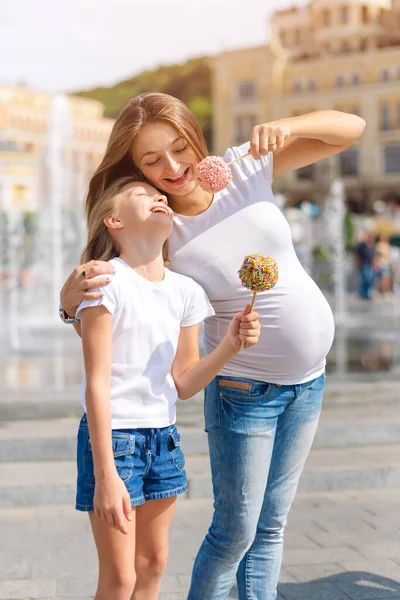 可爱的小女孩和她怀孕的妈妈在游乐场的集市上吃糖果苹果 快乐温馨的家庭 妈妈和女儿在一起很开心 — 图库照片