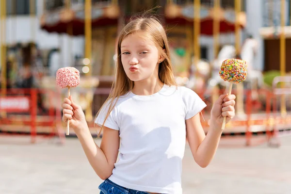 かわいい女の子食べるキャンディーアップルでフェアで遊園地 — ストック写真