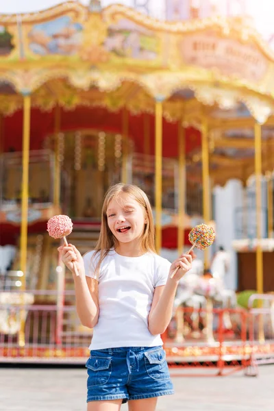 Tatlı Küçük Kız Elma Şekeri Yiyor Lunaparkta Poz Veriyor — Stok fotoğraf