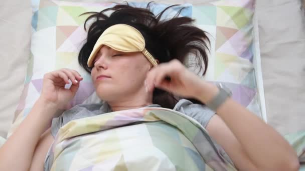 Top view on the young woman wearing sleep mask preparing for sleep, daytime sleep and relaxation. Lifestyle and people concept. Self isolation, home quarantine, social distancing. — Stock Video