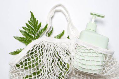 Yeşil şampuan, saç kremi ya da yeşil yapraklı ekolojik poşette sıvı sabun. İp torbası ya da doğal güzellik ürünleriyle dolu ağ torbası. Sıfır atık, çevre dostu kozmetik konsepti