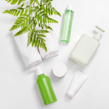 Yeşil bitkisel yapraklar ve su damlaları olan kozmetik kapları, markalaşma için boş etiket paketi. Nemlendirici krem, şampuan, tonik, yüz ve vücut bakımı. Doğal organik güzellik ürünü.
