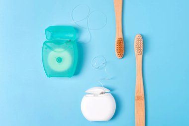 Diş ipi kapları ve mavi arka planda bambu diş fırçaları. Günlük ağız temizliği, diş bakımı ve sağlık. Ağız temizleme ürünleri. Diş sağlığı konsepti