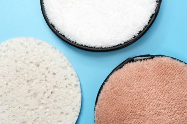 Mavi arka planda üç farklı yüz pufu. Güzellik, ten, saç veya vücut bakımı konsepti