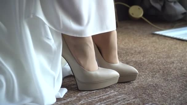 Nude shoes under a white long wedding dress. The bride puts on her shoes.
