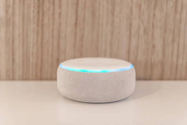 Amazon echo dot, Voice controlled speaker with activated voice recognition, on wood background.