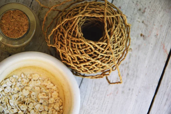 Doğal kozmetik yıkama konsepti için yulaf ezmesi tozu. İçine yulaf ezmesi dökülen beyaz bir havan topu, içine ubtan döküldüğü mantarlı yuvarlak bir cam şişe, bir rulo kağıt ambalaj.