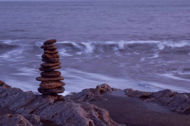 Deniz kıyısında mükemmel dengelenmiş çakıl taşı kulesi.