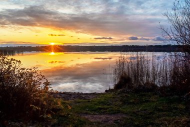 Gölün üzerinde güzel bir gün batımı. Suyun yansımasında güneş ışığı var.