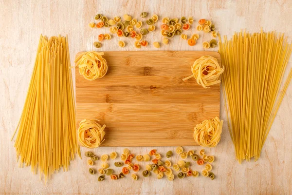 Different macaroni are laid out on a bamboo cutting Board and a — Stock Photo, Image