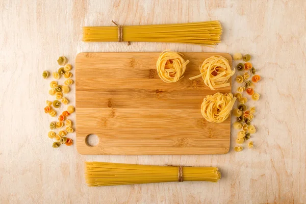 a small number of different types of pasta on a wooden backgroun