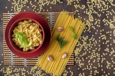 red ceramic Cup with a plate and Farfalle paste and a leaf of fr