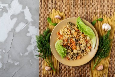 yellow ceramic Cup with pasta and fresh salad greens on a Mat of