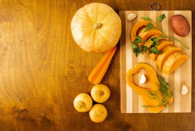sliced pumpkin with sprigs of dill and parsley on a bamboo cutti