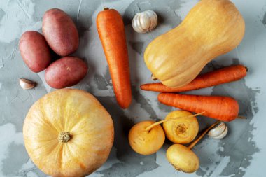 kabaklar, patatesler, şalgam, havuç ve sarımsak gri dokulu arka plan, üst manzara, düz oyun yemeği