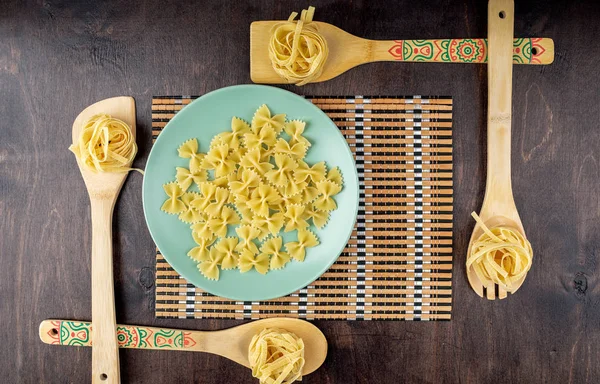 Farfalle Pasta Green Plate Fettuccine Bamboo Spatulas Dark Wooden Background — Stock Photo, Image