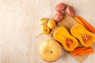 Bir bambu tahtasında iki parça balkabağı ve havuç, ve diğer sebzeler beyazlatılmış ahşap arka planda, üst manzara, yazı için yer, düz yiyecek.