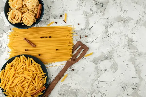 Verschiedene Trockene Pasta Blauen Tellern Und Gewürzten Spaghetti Auf Grau — Stockfoto