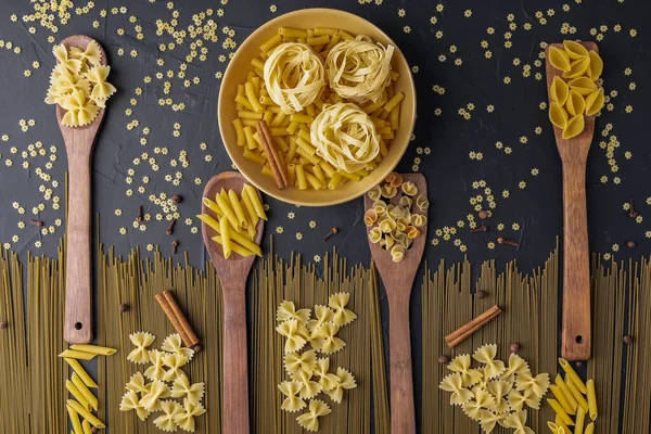 Yellow Ceramic Bowl Wooden Spatulas Variety Pasta Spices Black Textured — Stock Photo, Image