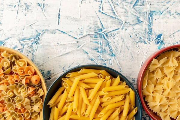 Rote Blaue Und Gelbe Schalen Mit Trockener Pasta Auf Weißem — Stockfoto