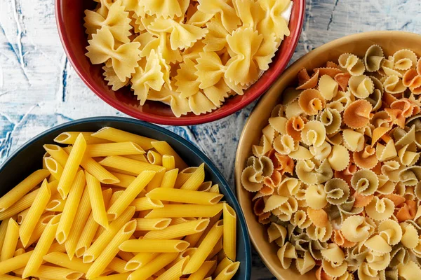 Cuencos Cerámica Azul Rojo Amarillo Con Diferentes Pastas Sobre Fondo Imagen de archivo