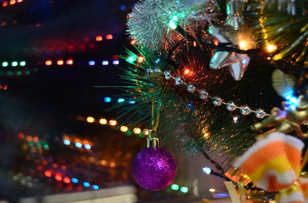 Pencere arkasında oyuncakları, boncukları ve ışıkları olan Noel ağacı dalı