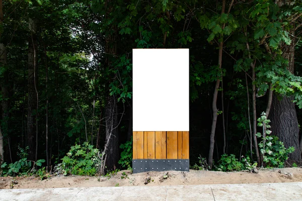 Blank vertical billboard on green grass in park to place your logo or advertising on it on wooden stand