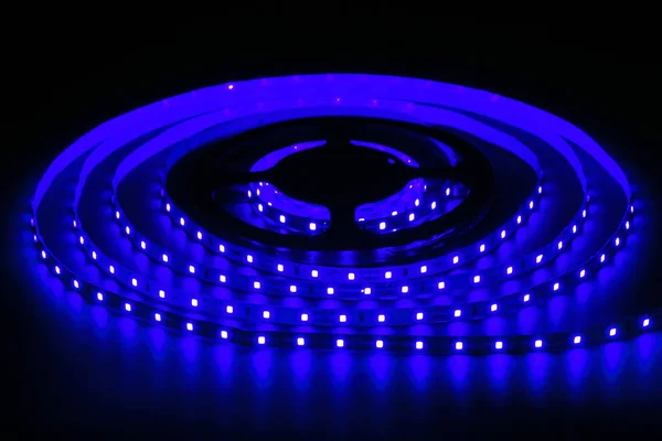 Blue LED strip on reel with black background.