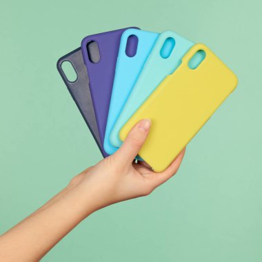 El ele tutuşan renkli kılıflar telefon için siyah, mavi, sarı arka planda.