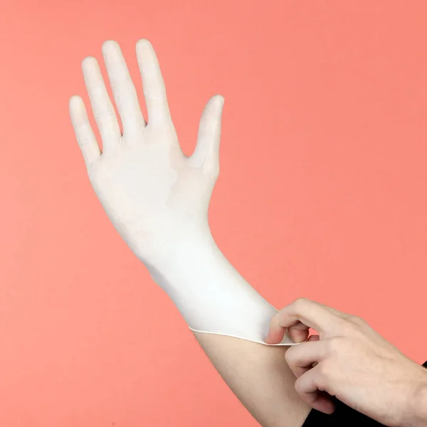 Mani di persona che indossa un guanto medico isolato su rosa — Foto Stock