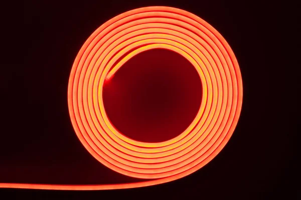 Flexible red LED neon strip on black background.