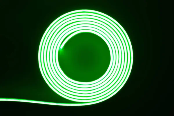 Flexible green LED neon strip on black background.