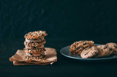 Koyu eski ahşap masa üzerinde çikolata parçacıklı kurabiyeler. Yeni pişirilmiş. Kopyalama alanı ile Seçici Odaklanma.