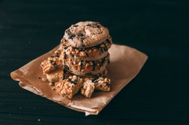 Koyu eski ahşap masa üzerinde çikolata parçacıklı kurabiyeler. Yeni pişirilmiş. Kopyalama alanı ile Seçici Odaklanma.