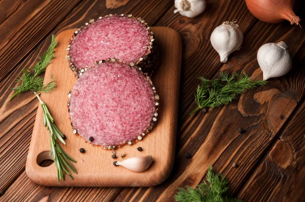 Rökt salami på ett gammalt träbord. Korv med rosmarin, vitlök och peppar — Stockfoto