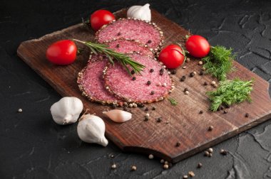 Siyah bir tablo ve bir kahverengi tahta üzerinde füme salam. Sosis ile 