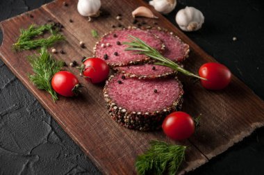 Siyah bir tablo ve bir kahverengi tahta üzerinde füme salam. Sosis ile 