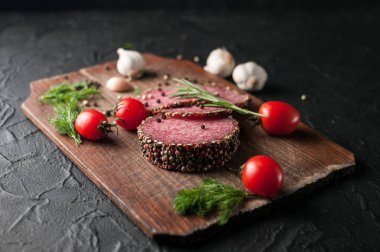 Siyah bir tablo ve bir kahverengi tahta üzerinde füme salam. Sosis ile 