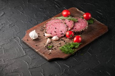 Siyah bir tablo ve bir kahverengi tahta üzerinde füme salam. Sosis ile 