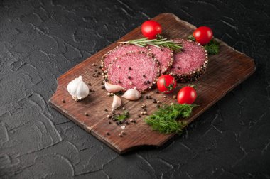 Siyah bir tablo ve bir kahverengi tahta üzerinde füme salam. Sosis ile 