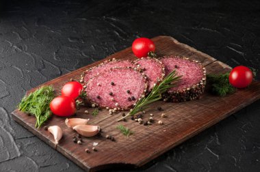 Siyah bir tablo ve bir kahverengi tahta üzerinde füme salam. Sosis ile 