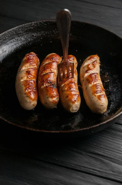 Sartén negra con deliciosas salchichas en la parrilla en la cocina ta —  Fotos de Stock