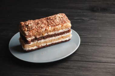 Geleneksel İtalyan tatlı tiramisu siyah ahşap zemin gri bir plaka üzerinde.