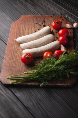 Siyah zemin ahşap bir kahverengi tahtada üç çiğ sosis