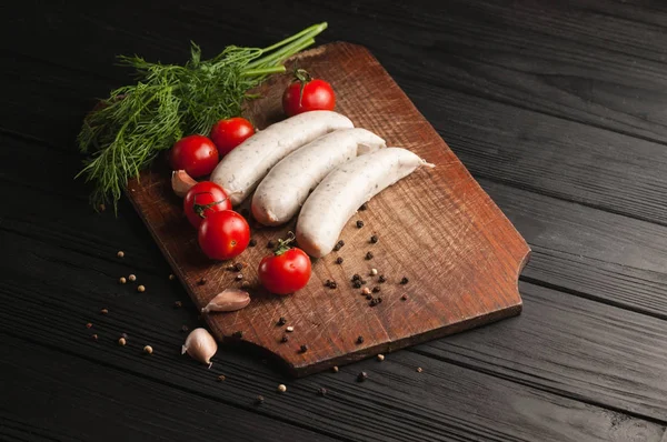 Drie rauwe worstjes op een houten bruin bord op een zwarte achtergrond — Stockfoto