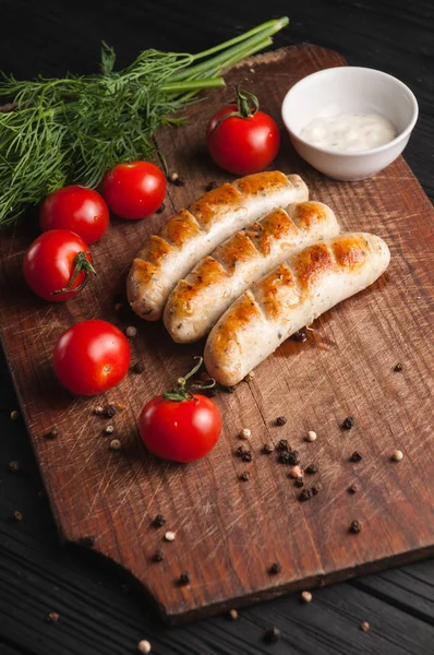 Grilled sausages grilled on a brown wooden board on a wooden bac